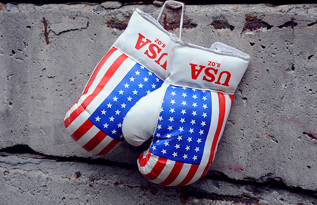 Used boxing gloves with US flag on them on the shabby concrete fence