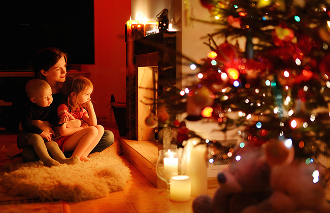 Young mother and her daughters by a fireplace on Christmas