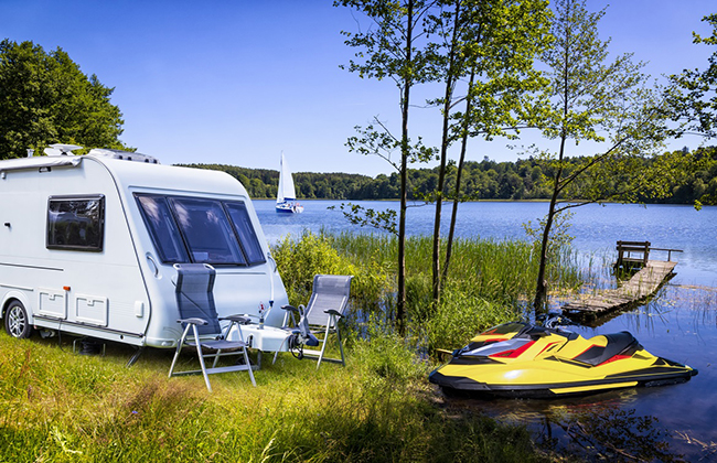 Vacations in Poland - Summer view of camper trailer on the shore of the Drawsko lake