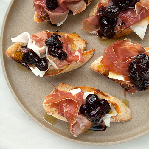 Crostini with Stewed Black Grapes, Prosciutto, and Ricotta Salata