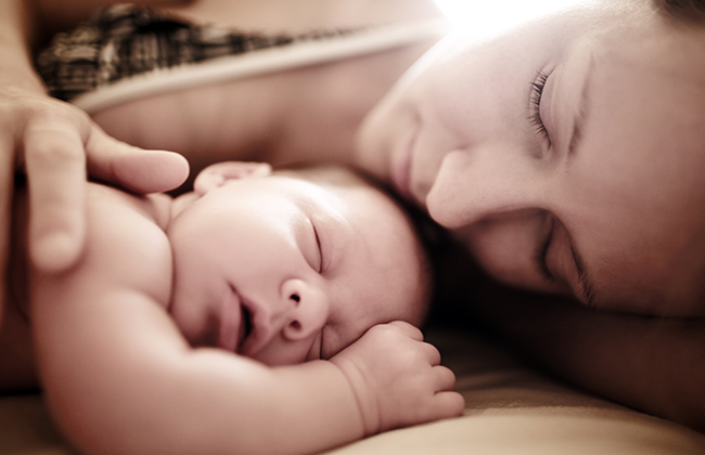 Newborn baby sleeping with mother. Shallow DOF.